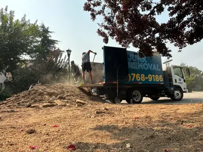 Top Shelf crew shoveling yard debris into junk removal truck in Boise Idaho